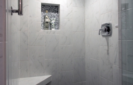 Bathroom remodeling, large walk-in shower stall with bench seating, frame less shower door, large wall tile.
